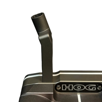 Close-up of a HOG golf putter head in a dark metallic gray finish, featuring a vertical neck and the HOG logo on the front, set against a dark textured background.